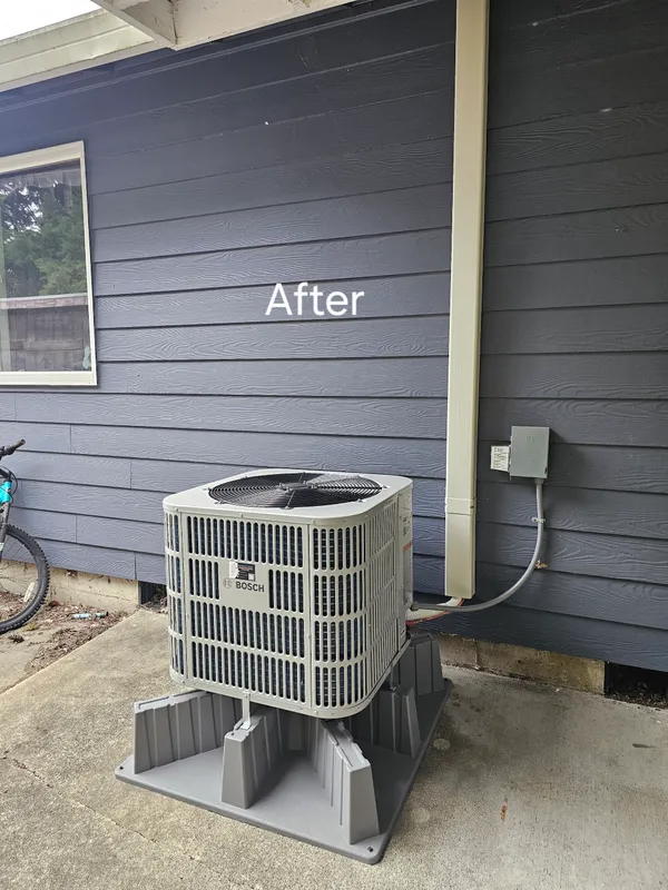 Bosch heat pump installed against navy siding - completed installation