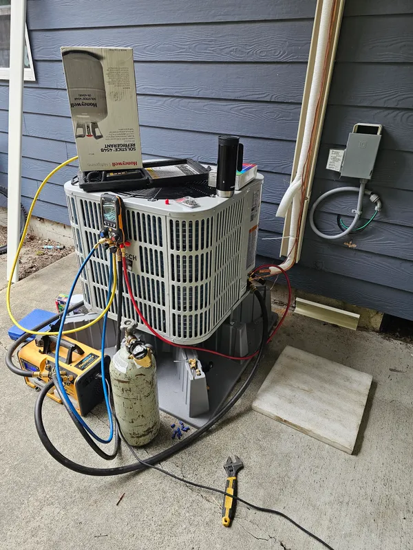 HVAC technician performing diagnostics on a Bosch heat pump with gauges and refrigerant equipment